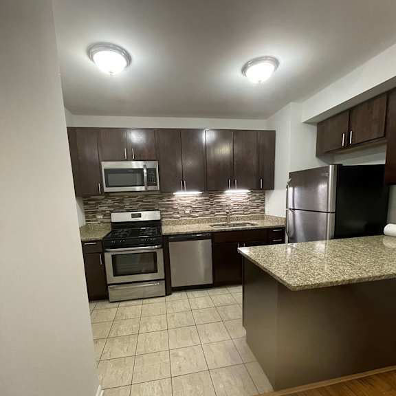 a kitchen with dark cabinets and a white tile floor