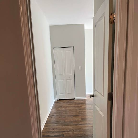 a hallway with wood floors and a white door