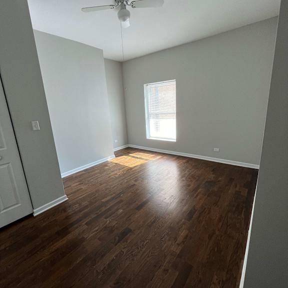 an empty living room with wood floors and a ceiling fan