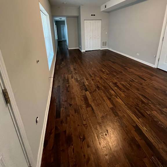 a living room with a hard wood floor and a door into a bedroom