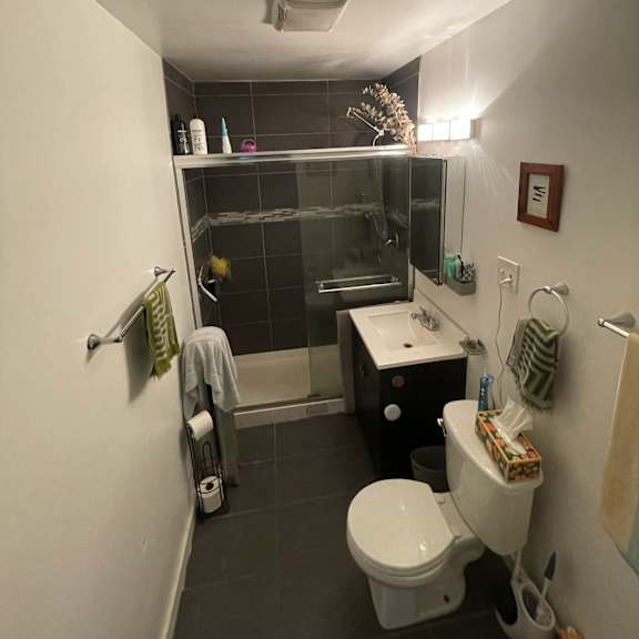 a small bathroom with a toilet, sink, and shower.