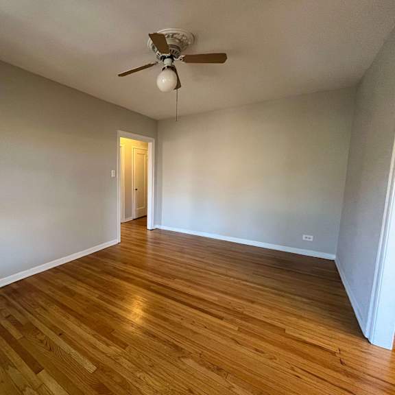 a room with wooden flooring and a ceiling fan.