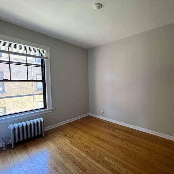 a room with wooden floors and a window with blinds.