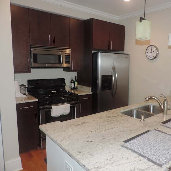 a kitchen with a marble counter top and a stainless steel refrigerator