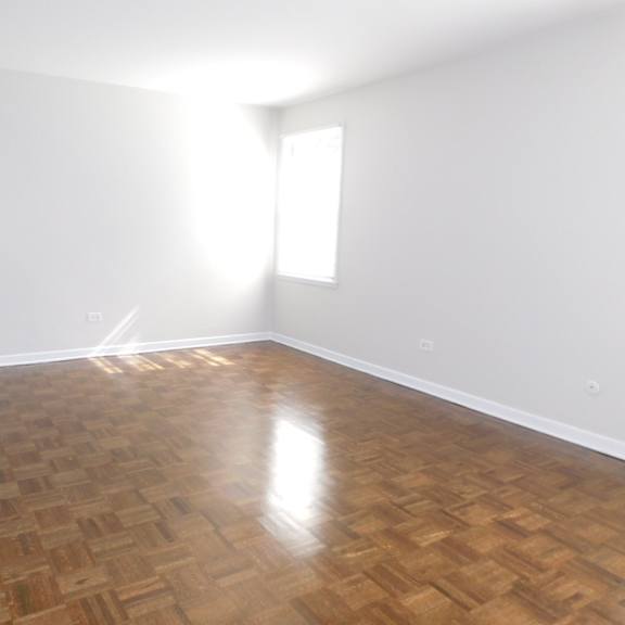 a room with wooden flooring and a window letting in sunlight.