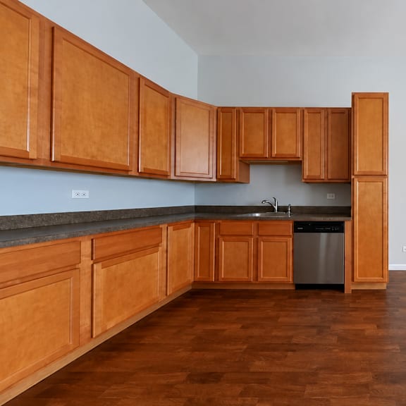 a kitchen with wooden cabinets and a trash can.