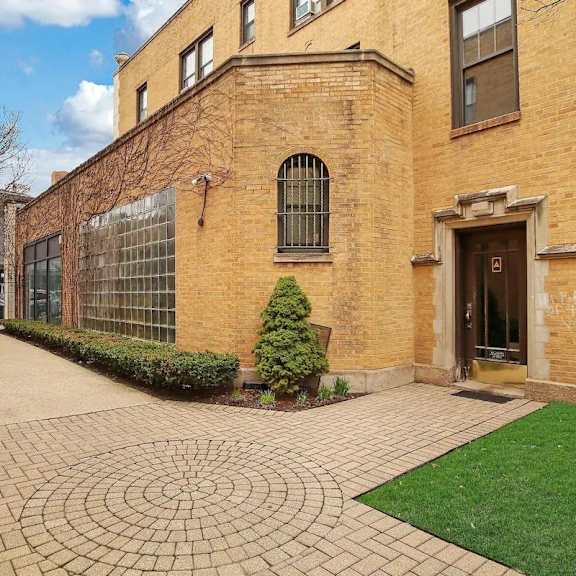 the exterior of a brick building with a walkway and grass