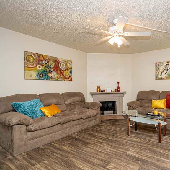 A living room with a brown couch, a fireplace, and a painting on the wall.
