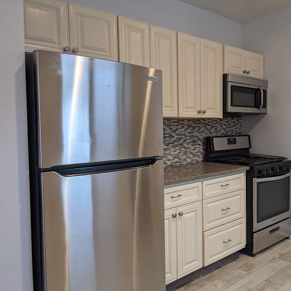 a kitchen with a stainless steel refrigerator, microwave, and stove.