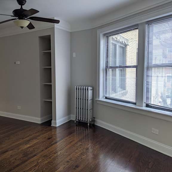 a room with a ceiling fan and a radiator on the wall.