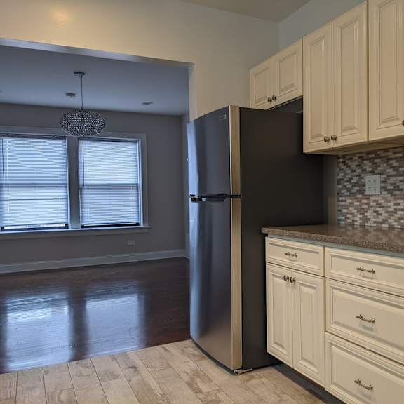 a kitchen with a black refrigerator and white cabinets.