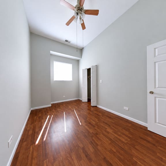 a room with a ceiling fan and wooden floors.