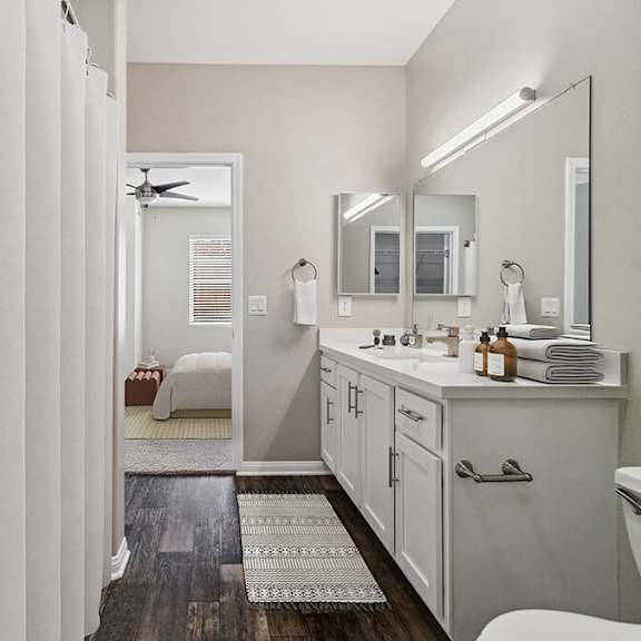 model bathroom with white cabinets, wood-style flooring & shower/tub at reserve at rancho apartments located in moreno valley, ca.