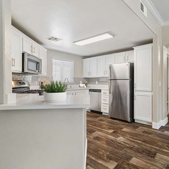 model kitchen with white cabinets and wood-style flooring at reserve at rancho apartments located in moreno valley, ca.