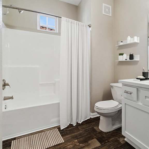 model bathroom with white cabinets, wood-style flooring & shower/tub at reserve at rancho apartments located in moreno valley, ca.