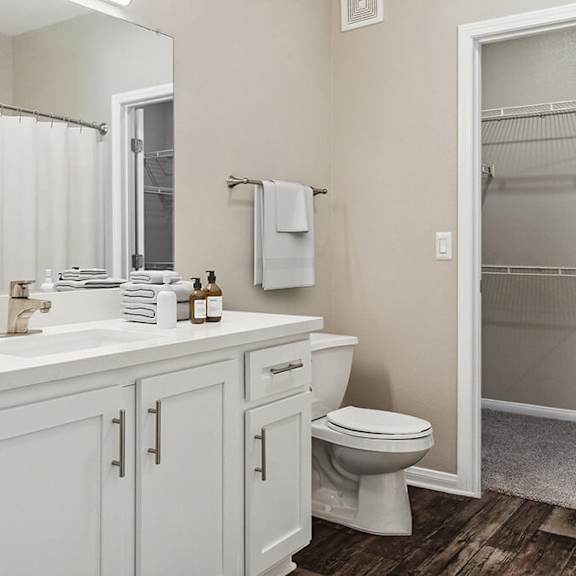 model bathroom with white cabinets, wood-style flooring & walk in closet at reserve at rancho apartments located in moreno valley, ca.