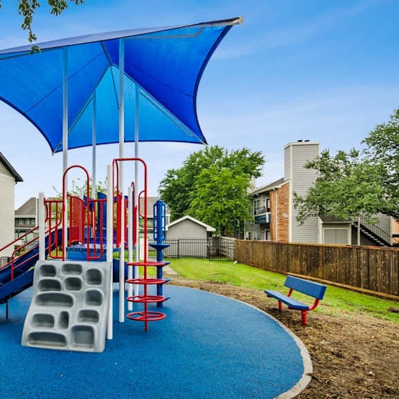 a playground with a swing set and a blue umbrella