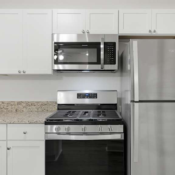 a kitchen with a stove, microwave, and refrigerator.