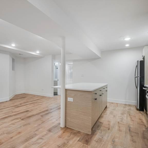 a spacious room with wooden flooring and white walls.