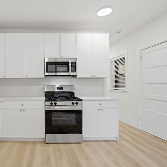 a modern kitchen with white cabinets and stainless steel appliances.