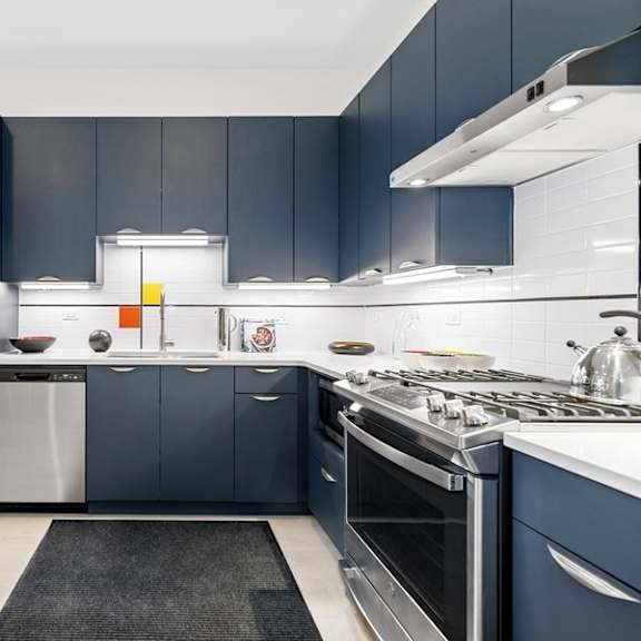 a kitchen with dark blue cabinets and stainless steel appliances