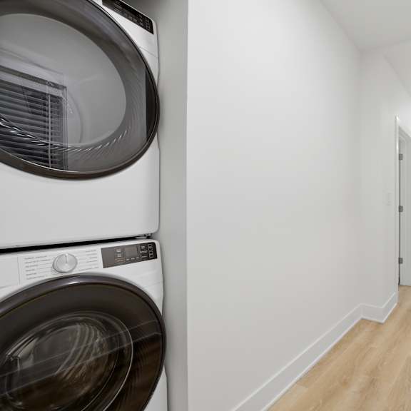 a white washing machine is on the left of a hallway.
