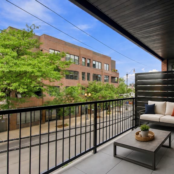 a balcony with a black railing and a table with a bowl on it.