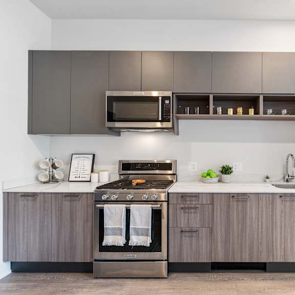 a kitchen with gray cabinets and brand-new stainless steel appliances