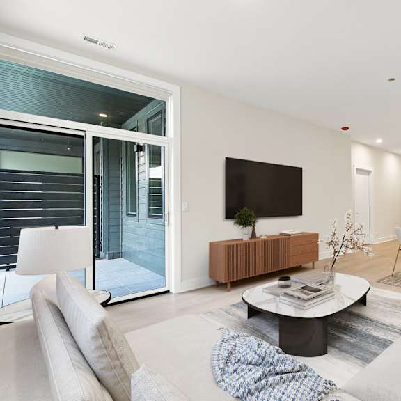 a modern living room with a flat screen tv and a glass door leading to a balcony.