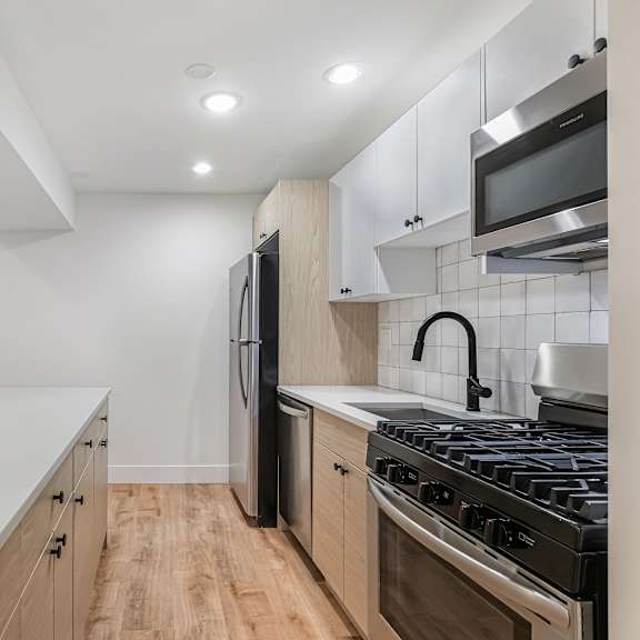 a modern kitchen with a white countertop and stainless steel appliances.