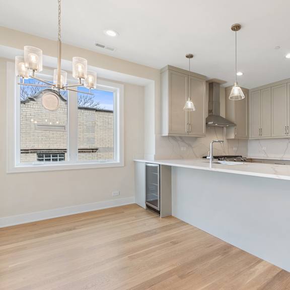a white kitchen with a large island and a stainless steel refrigerator