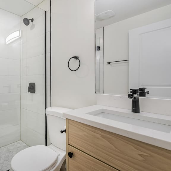a white bathroom with a toilet, sink, and shower.