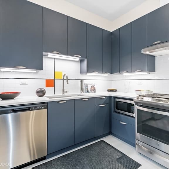 a modern kitchen with blue cabinets and stainless steel appliances