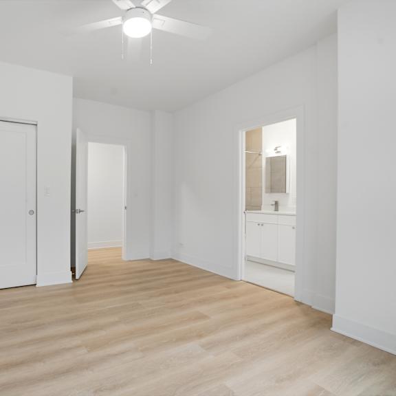 a room with white walls and wooden flooring with a ceiling fan.