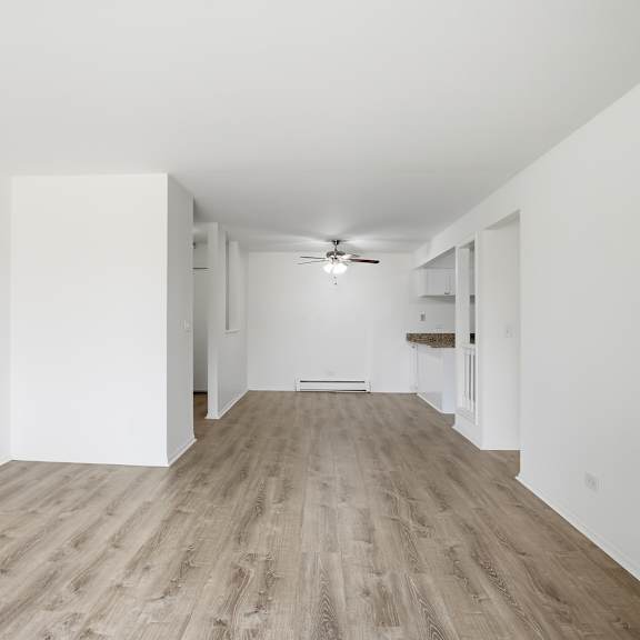 a long, empty hallway with wood flooring and white walls.