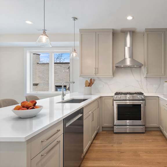 a modern kitchen with stainless steel appliances and wooden floors.
