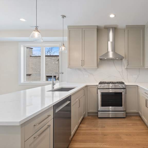 a white kitchen with stainless steel appliances and white counter tops