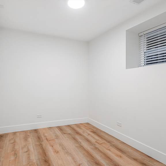 a room with wooden flooring and a window with blinds.