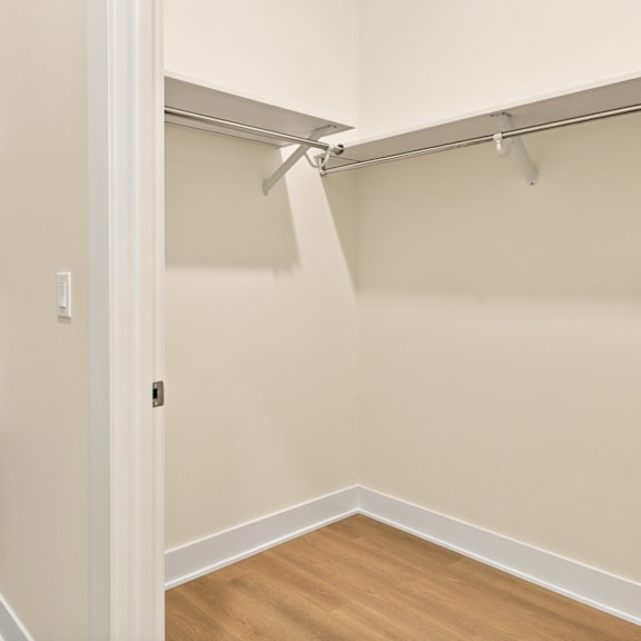 a white closet with a wooden floor and a white door.