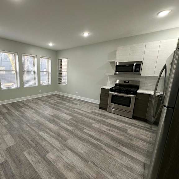 a spacious kitchen with a grey floor and stainless steel appliances.