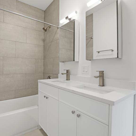a white bathroom with a white tub, sink, and vanity.