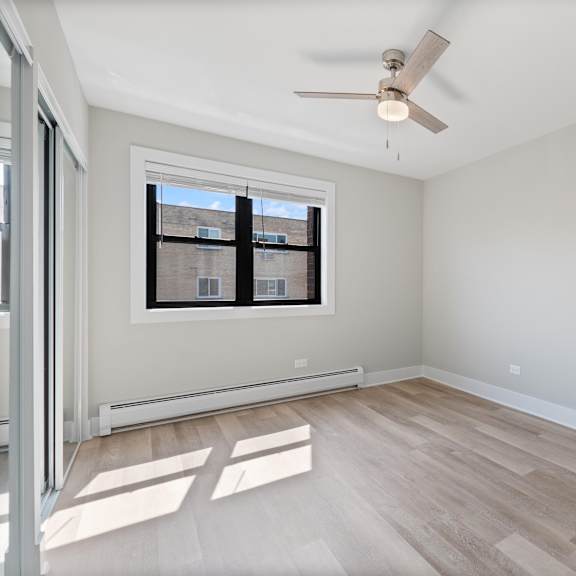 a bedroom with hardwood floors and a ceiling fan