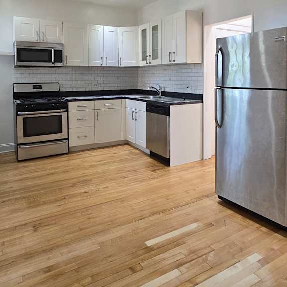 a kitchen with wooden floors and white walls.