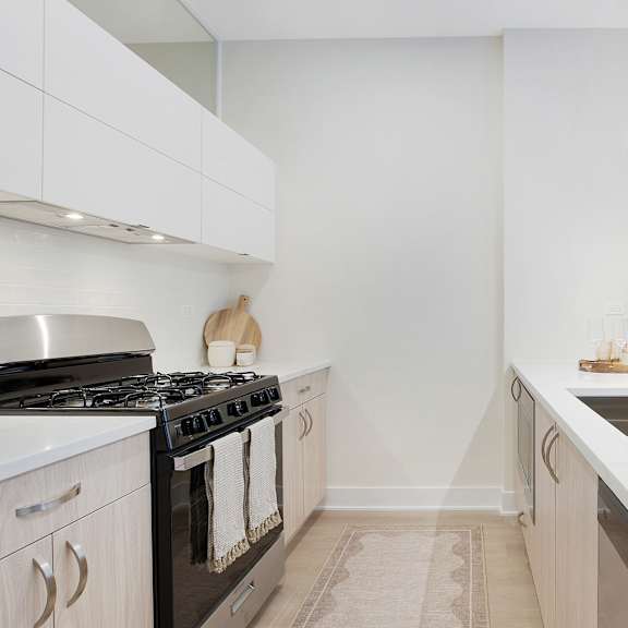 a modern kitchen with a black stove and white cabinets.