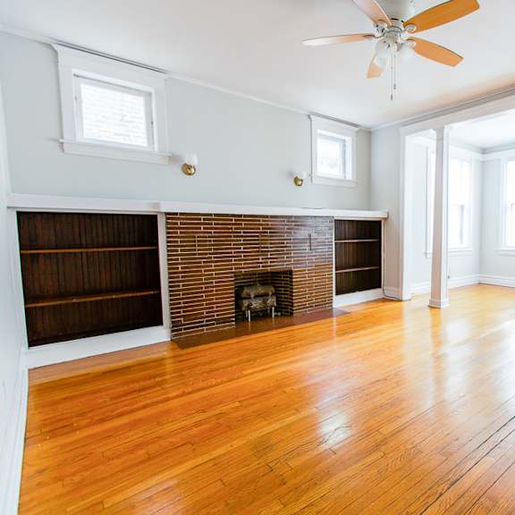 an empty living room with wood floors and a brick fireplace