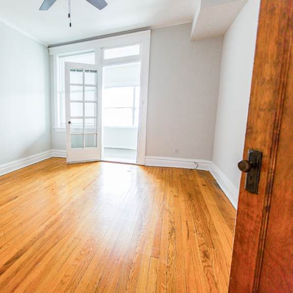 an empty living room with wood floors and a door to a balcony