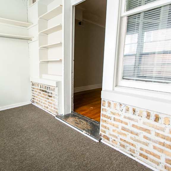 a doorway into a room with a brick wall and a window