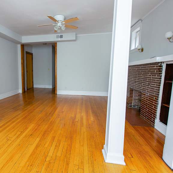 an empty living room with wood floors and a ceiling fan