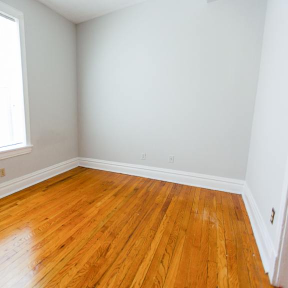 an empty room with wooden floors and two windows