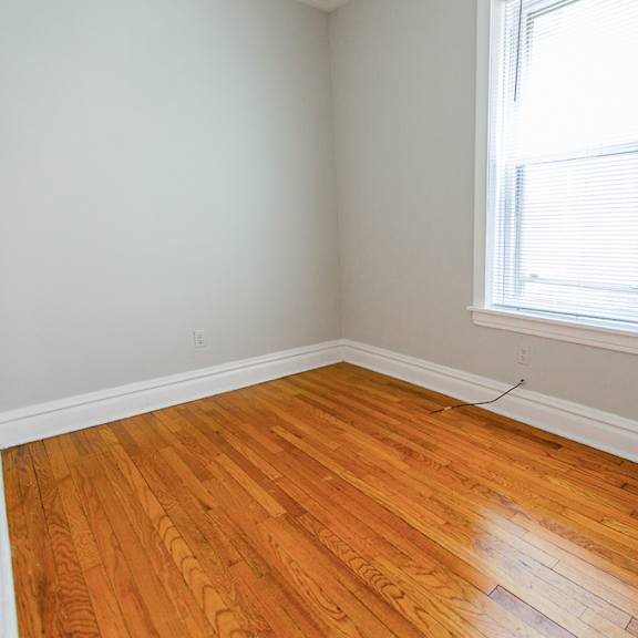 an empty room with wooden floors and a window